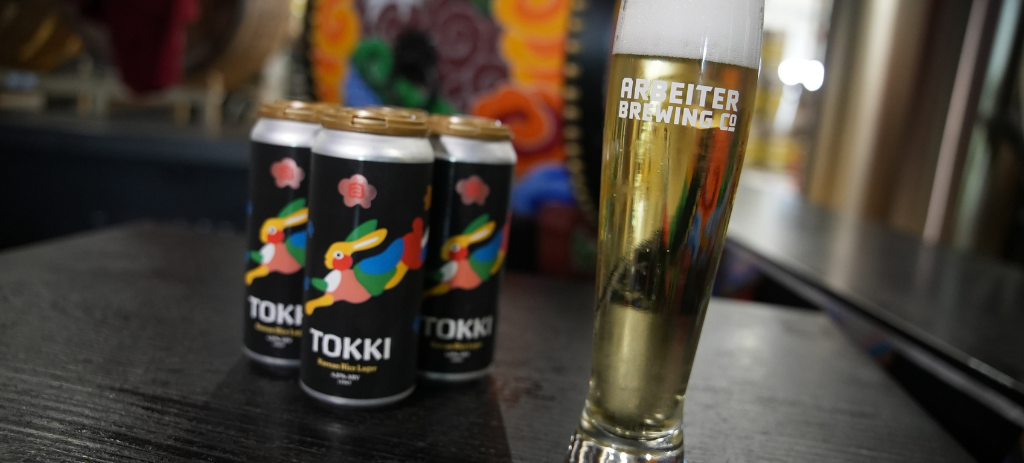 Cans and glass of Tokki Korean Rice Lager at Arbeiter Brewing Co.
